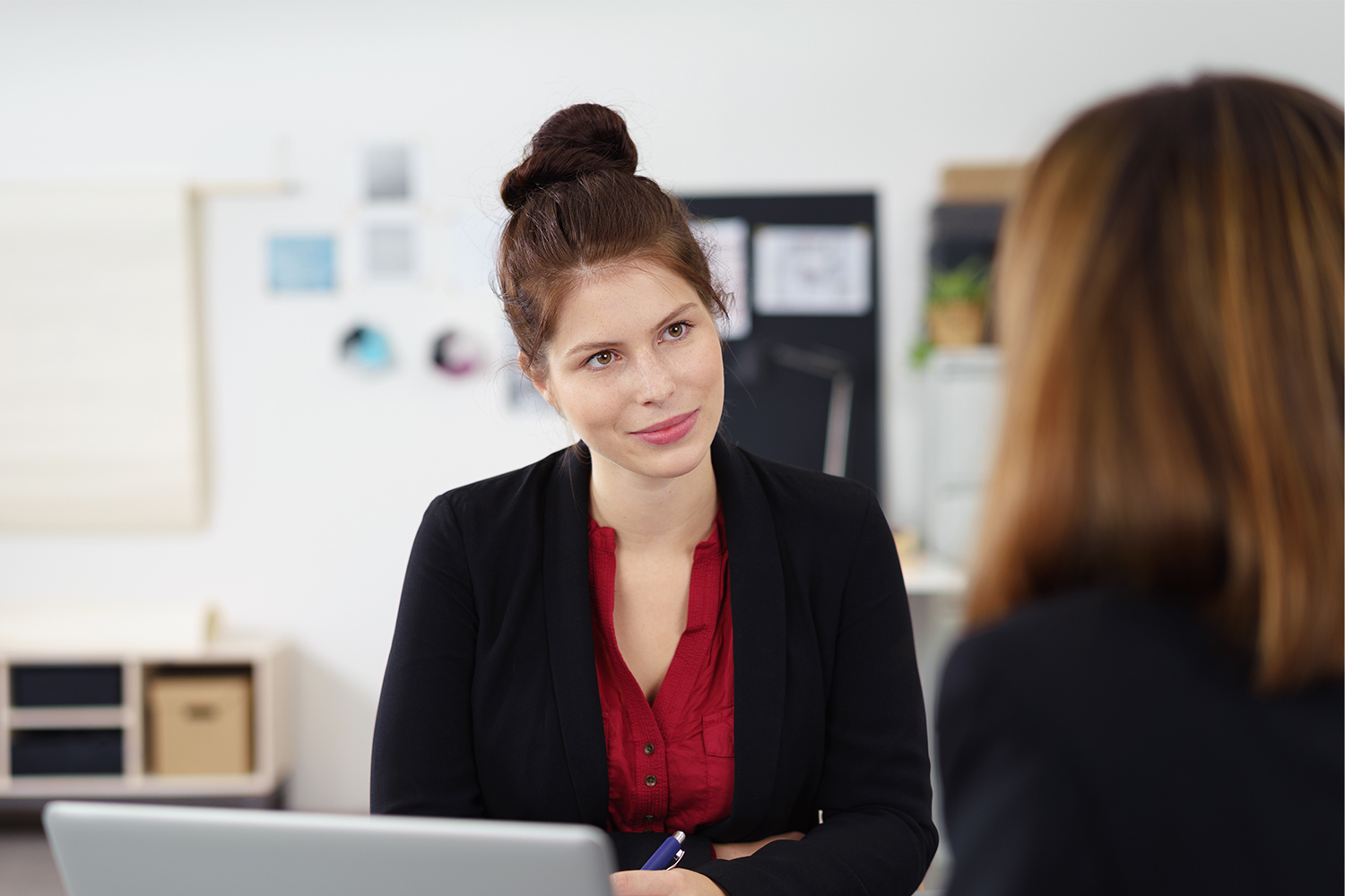 Zwei Männer und eine Frau stehen um ein Pult in einem Büro.