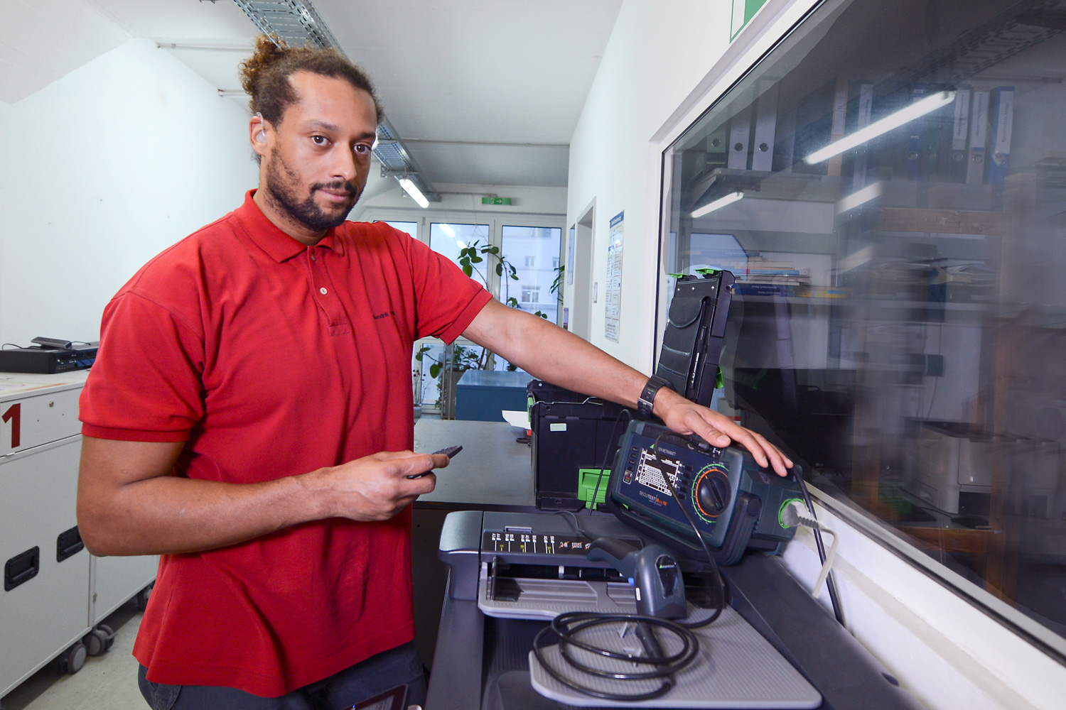 Ein Mann am Drucker mit einem Gerät für das E-Controlling