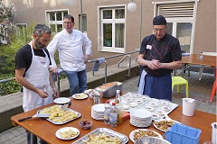 Drei Männer schauen nach dem Kochen auf das fertige Essen